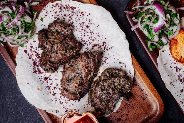 Churrasco de carne no lavash com rolos de cebola e sumakh.