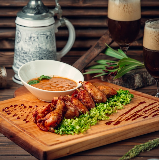 Churrasco de frango em alface verde com uma tigela de molho de tomate.