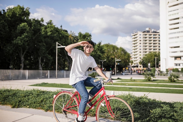 Ciclista adolescente andando de bicicleta e protegendo os olhos