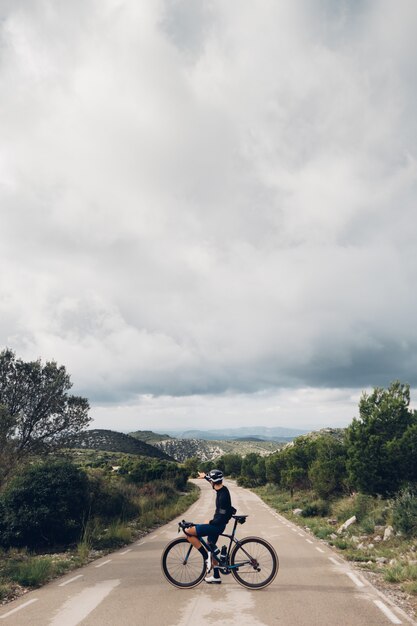 Ciclista andando de bicicleta ao pôr do sol em uma estrada na montanha