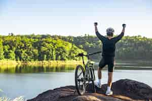 Foto grátis ciclista de bicicleta de montanha em pé no topo de uma montanha com bicicleta