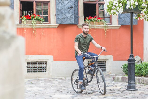 Ciclista masculina andando de bicicleta em frente ao prédio