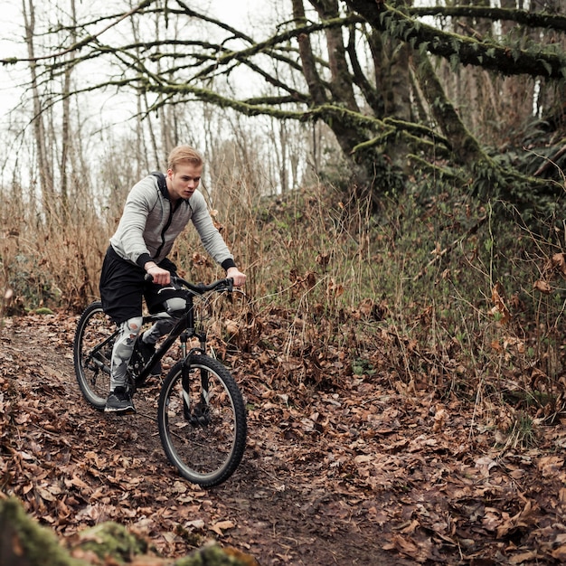 Foto grátis ciclista masculina andando na trilha da floresta