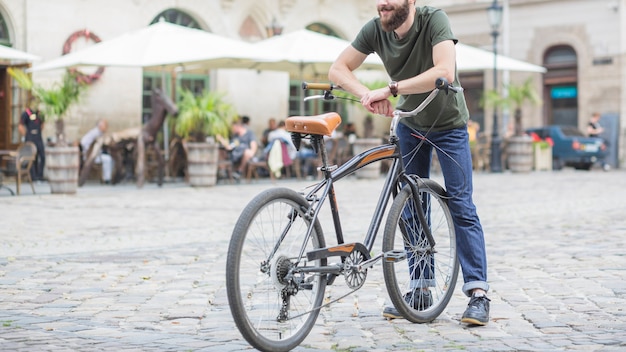 Ciclista masculina com bicicleta em pé na rua da cidade