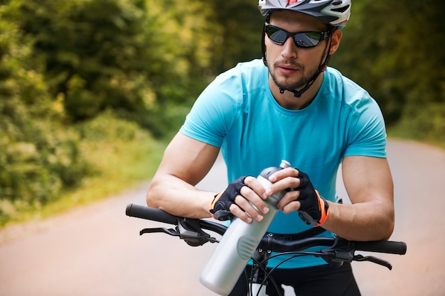 Ciclista pensativo em pé na estrada