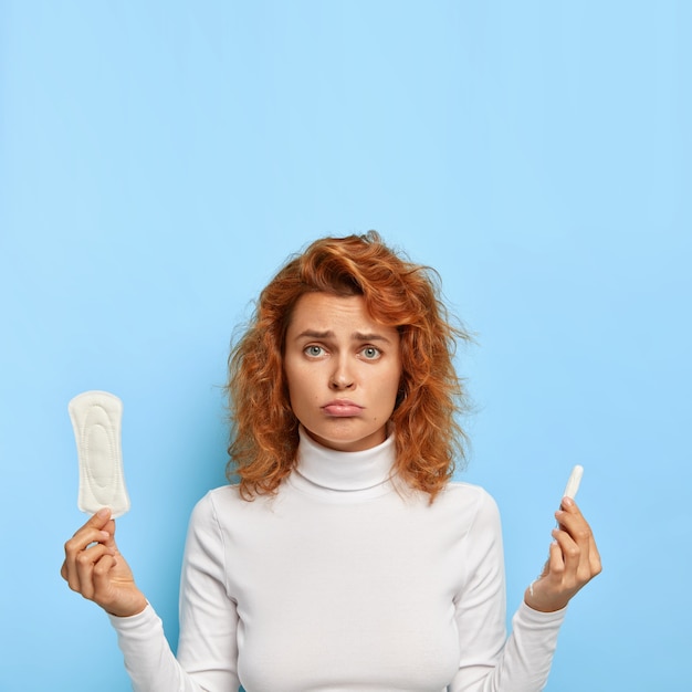 Ciclo menstrual e conceito de saúde das mulheres. mulher insatisfeita segurando absorvente higiênico e absorvente interno