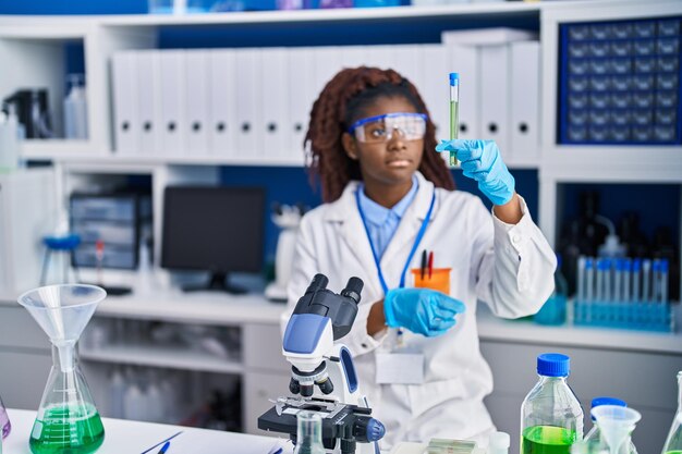 Cientista afro-americana segurando tubo de ensaio no laboratório