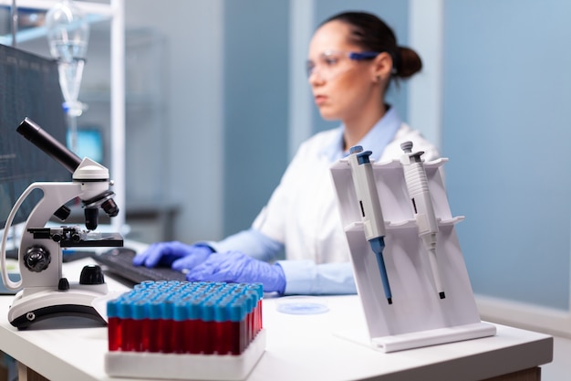 Foto grátis cientista da microbiologia digitando experimento de descoberta de bioquímica no computador