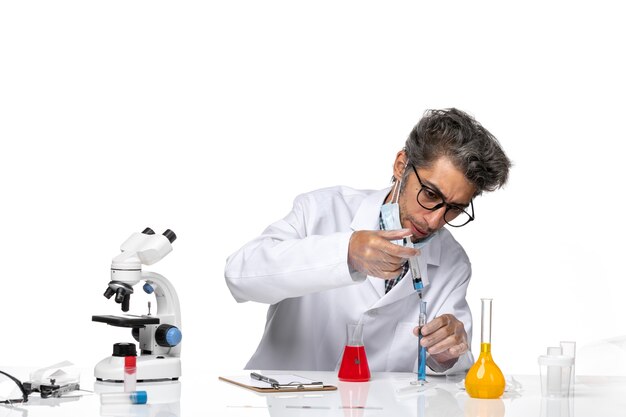 Cientista de meia-idade de vista frontal em traje médico branco preparando a injeção