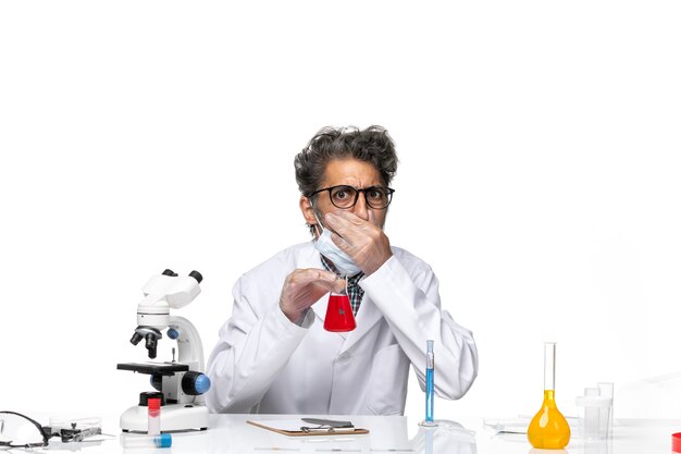 Cientista de meia-idade usando uma solução especial para cheirar um terno branco
