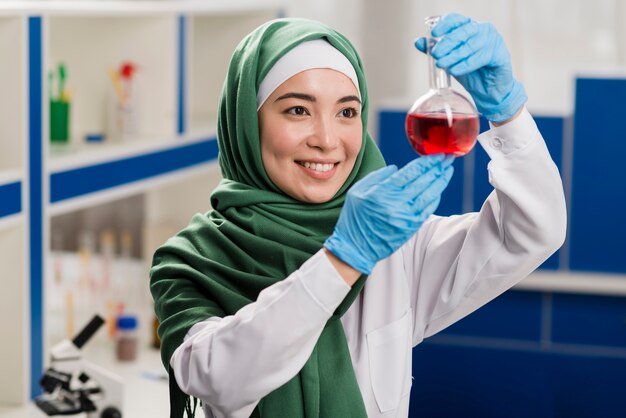 Cientista fêmea com hijab olhando substância no laboratório