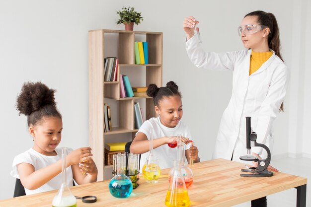 Cientista fêmea ensinando meninas experiências científicas