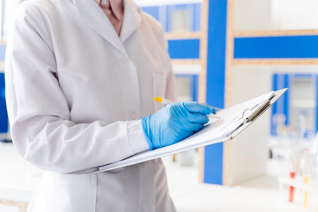 Foto grátis cientista feminina no laboratório com o bloco de notas