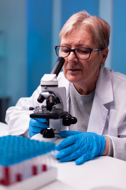 Cientista sênior examinando ao microscópio uma amostra no laboratório de biologia