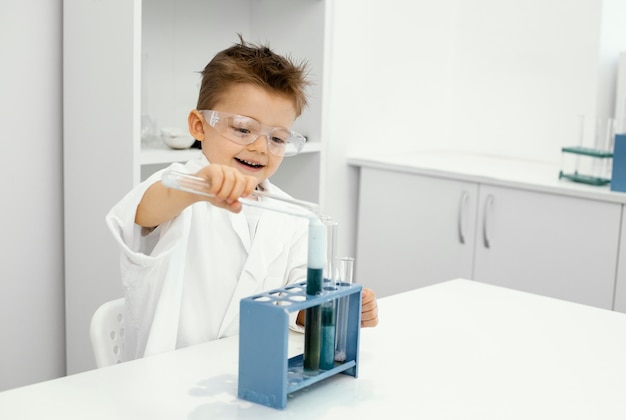 Foto grátis cientista sorridente no laboratório com tubos de ensaio fazendo experimentos