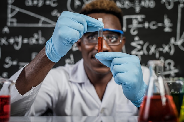 Foto grátis cientistas examinam os produtos químicos alaranjados no vidro do laboratório