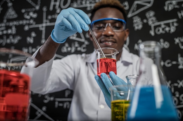 Cientistas que misturam produtos químicos vermelhos no vidro no laboratório.