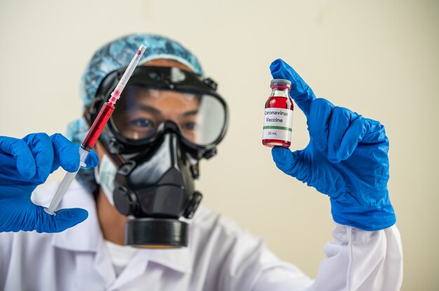 Cientistas usando máscaras e luvas Segurando uma seringa com uma vacina para prevenir a covid-19