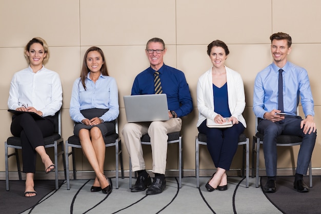 Foto grátis cinco candidatos sorrindo sentado na sala de espera