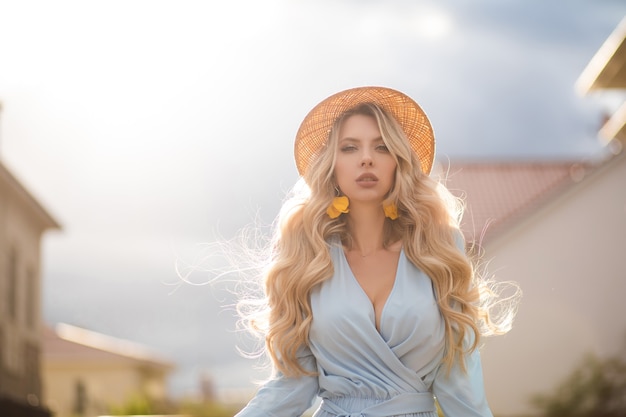 Cintura de mulher jovem com vestido de verão e chapéu de palha enquanto caminhava na rua da cidade. conceito de beleza e moda