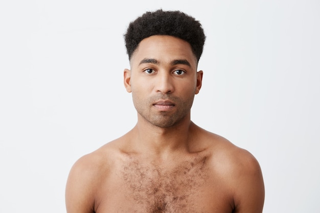 Foto grátis cintura para cima o retrato da foto do homem africano de raça mista de pele negra com cabelo escuro encaracolado, sem roupa, olhando na câmera com a expressão do rosto relaxado.