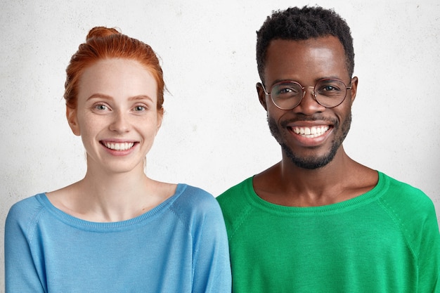 Foto grátis cintura para cima retrato de casal de raça mista com sorrisos largos e calorosos, felizes por passarem tempo juntos.