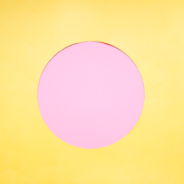 Foto grátis círculo rosa sobre fundo amarelo