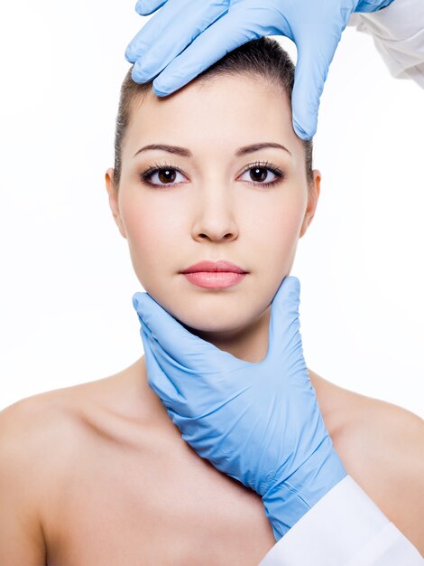 Cirurgia plástica tocando o rosto de mulher bonita. Isolado no branco