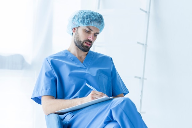 Foto grátis cirurgião concentrado escrevendo na área de transferência