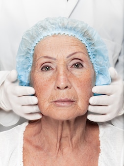 Cirurgião que faz a verificação da pele na mulher de meia idade antes da cirurgia plástica