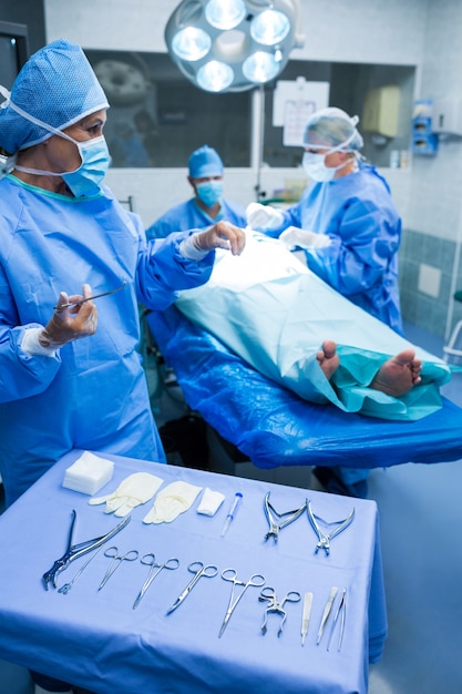 Cirurgião que olham tesoura no quarto de operação