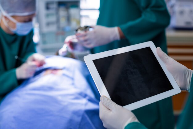 Cirurgião usando tablet digital durante a operação do paciente na sala de operações