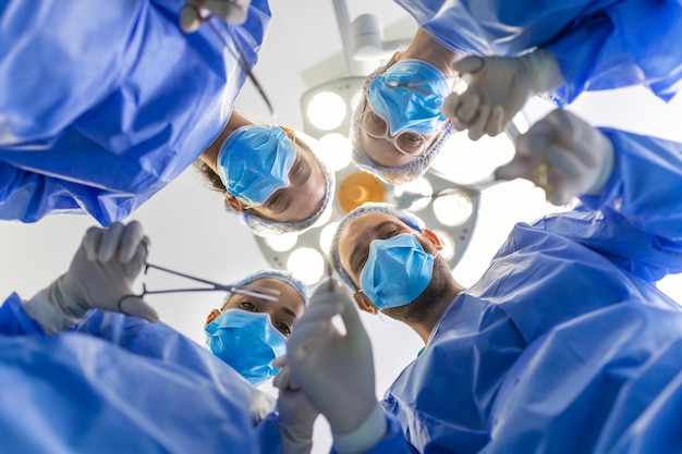 Foto grátis cirurgiões em pé acima do paciente antes da cirurgia profissionais de saúde multiétnicos realizando cirurgia em paciente no centro cirúrgico