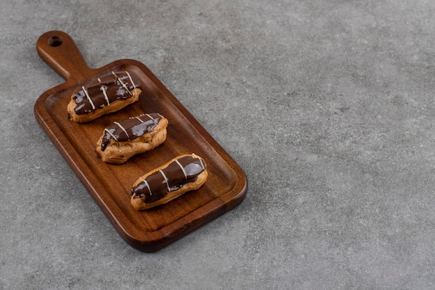 Éclairs de chocolate frescos caseiros em uma tábua de madeira