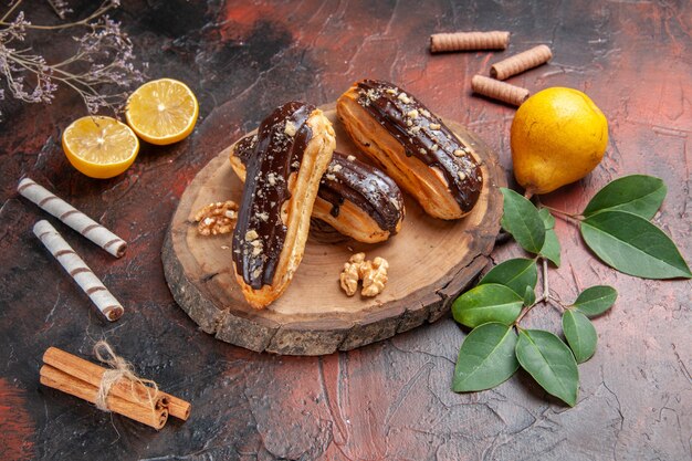 Éclairs de chocolate saborosos com frutas na mesa escura bolo sobremesa doce