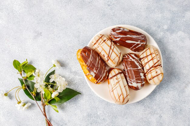 Éclairs ou profiteroles com chocolate preto e chocolate branco com creme dentro, sobremesa francesa tradicional.