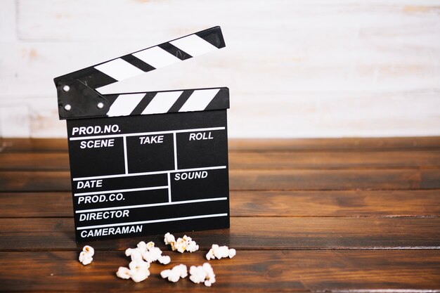 Clapperboard e pipoca em mesa de madeira