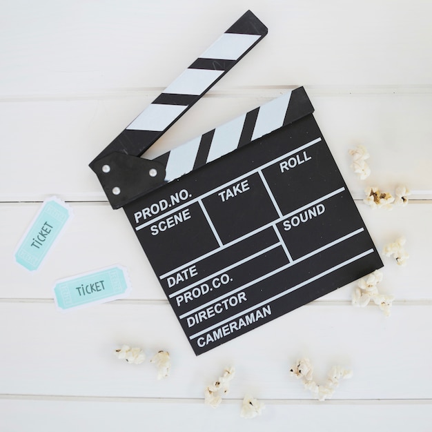 Foto grátis clapperboard perto de pequenos bilhetes de cinema e pipoca