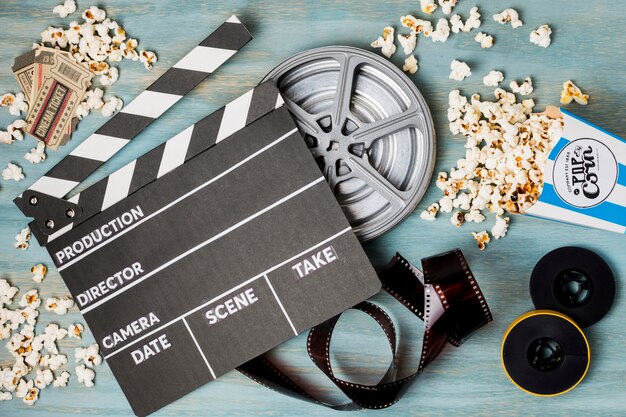Claquete; Pipoca; faixa de filme e bilhetes de cinema na mesa de madeira