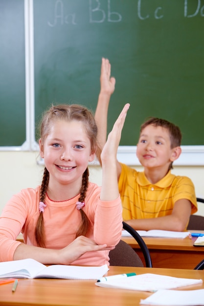 Classmates levantando as mãos na sala de aula para uma resposta