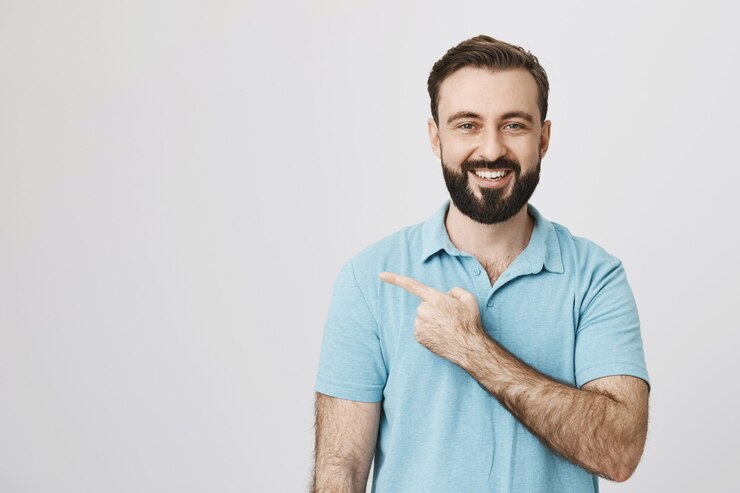 Foto grátis cliente do sexo masculino satisfeito e feliz, sorrindo e apontando para a esquerda para a copyspace