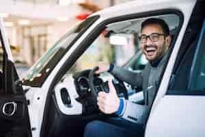 Foto grátis cliente feliz e satisfeito acaba de comprar um carro novo em uma concessionária