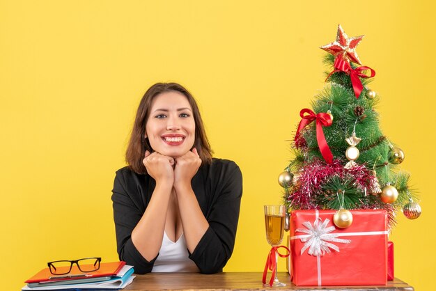 Clima de ano novo com uma linda mulher de negócios feliz e sentada à mesa do escritório