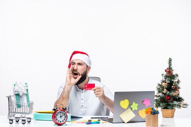 clima de natal com jovem adulto com chapéu de Papai Noel, segurando o cartão do banco e gritando com alguém no escritório