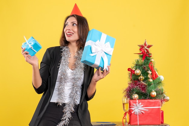 Clima de natal com uma linda senhora segurando presentes alegremente no escritório em amarelo