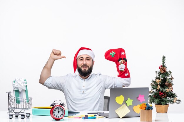 clima natalino com adulto jovem positivo com chapéu de Papai Noel e usar meia de natal na mão fazendo gesto de força no escritório