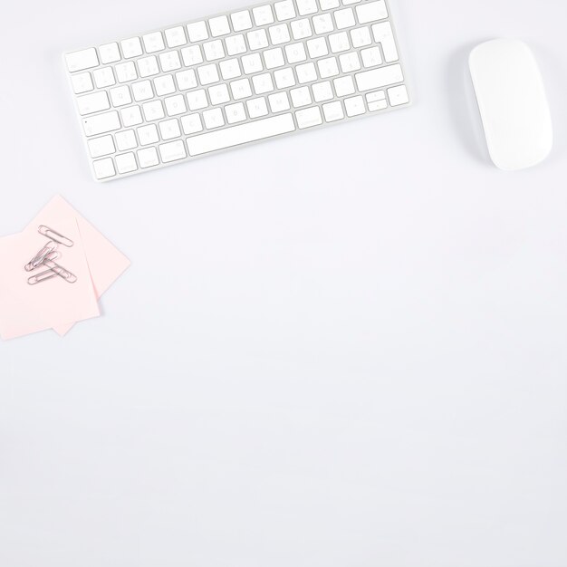Clipes de papel e notas adesivas perto de teclado e mouse