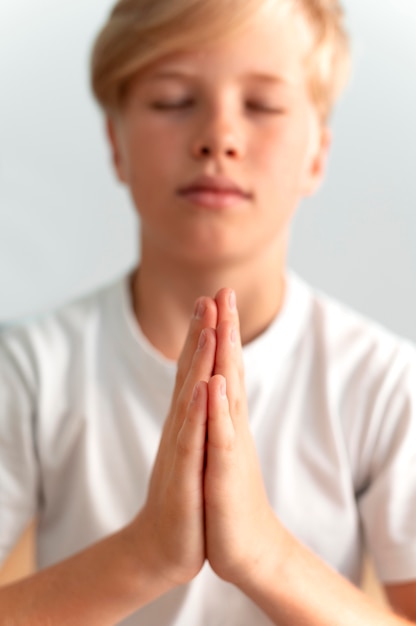 Close, criança meditando dentro de casa