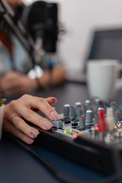 Close da mão empurrando os controles no console de mixagem de som. Pessoa que trabalha com controlador de áudio digital para gravar podcast. Botões de controle de mídia de dublagem para produção de gravação ao vivo.