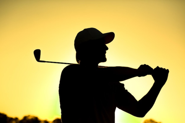 Close da silhueta negra de jogador de golfe masculino com chapéu na tacada inicial no lindo campo de golfe Jogador de golfe profissional sorrindo